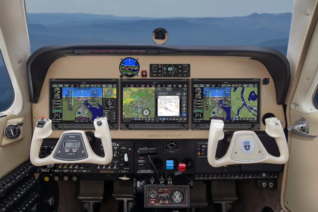 A Beechcraft Bonanza instrument panel fitted with three Garmin AXIS 11.6-inch flight displays. Radio frequencies and audio controls appear along the top of each display rather than in a separate centre stack.